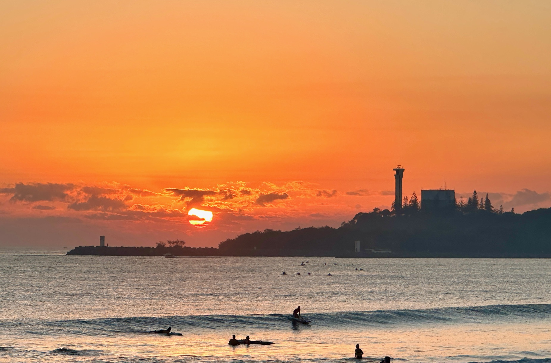 Sunset over a Sunshine Coast beach with surfers in the water